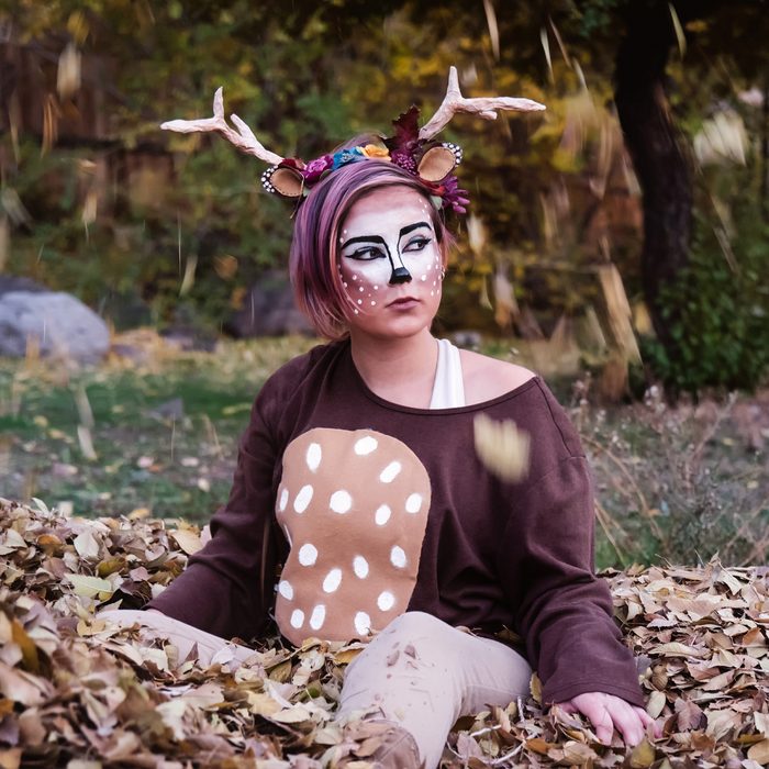 Girl Sitting In A Pile Of Leaves Dressed As A Deer