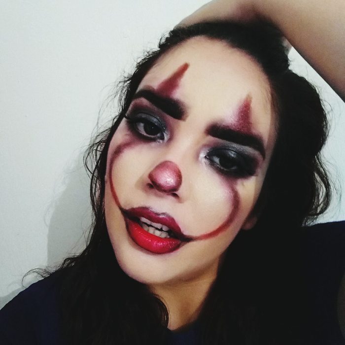 young woman with scary clown face paint for halloween