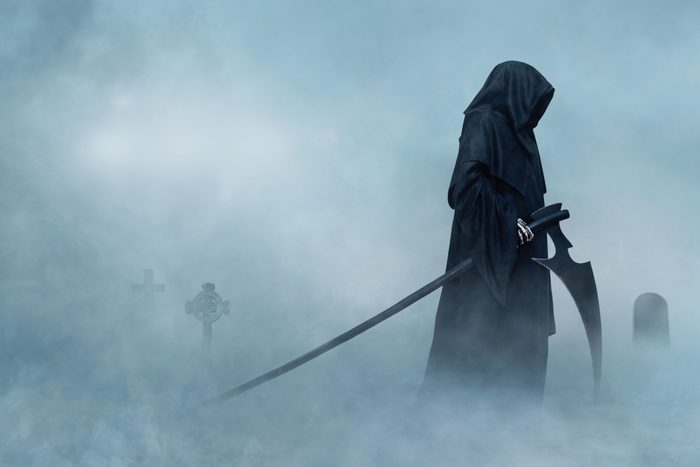 the Grim Reaper walking in a foggy cemetary.