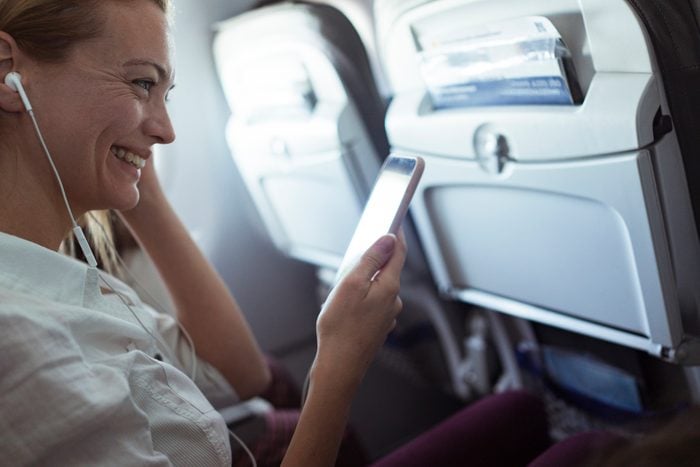 Young woman using a phone while traveling in an airplane