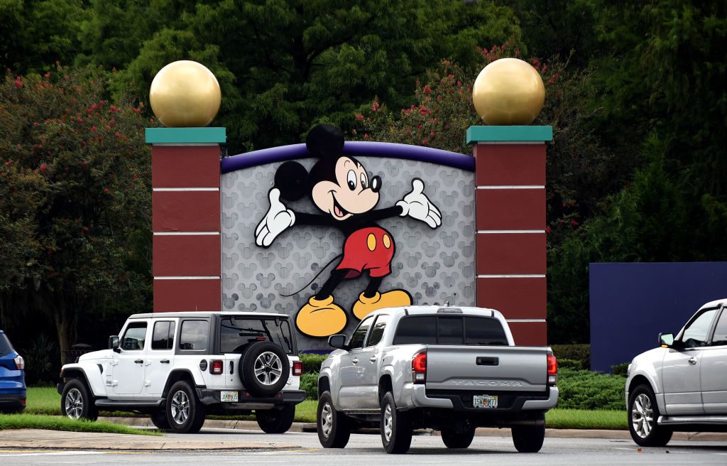 Cars drive past a sign featuring Mickey Mouse at the...