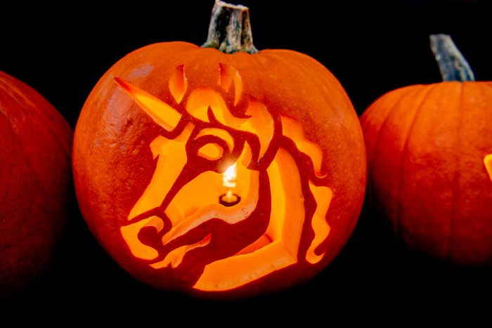 a unicorn carved into a pumpkin with a candle inside