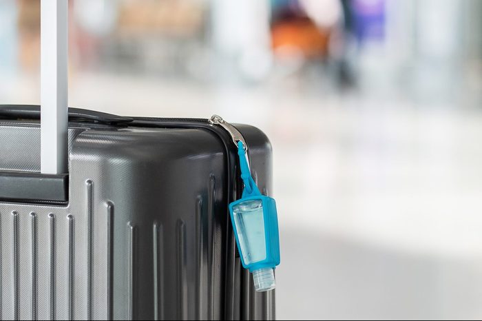 Luggage bag with alcohol gel hand sanitizer in international airport terminal, protection Coronavirus disease (Covid-19) infection. New Normal and travel bubble concepts