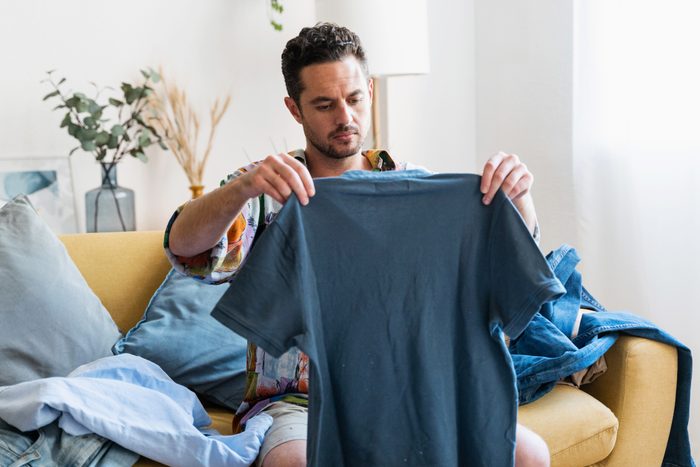 man looking at a blue shirt that shrunk in the wash