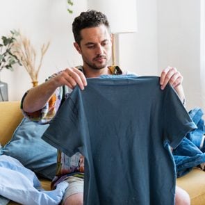 man looking at a blue shirt that shrunk in the wash