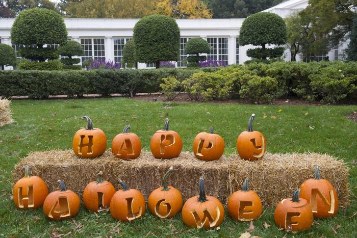 Carved pumpkins in line spelling out "happy Halloween" on front lawn