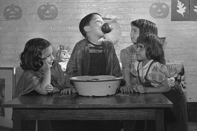 children bobbing for apples at halloween party