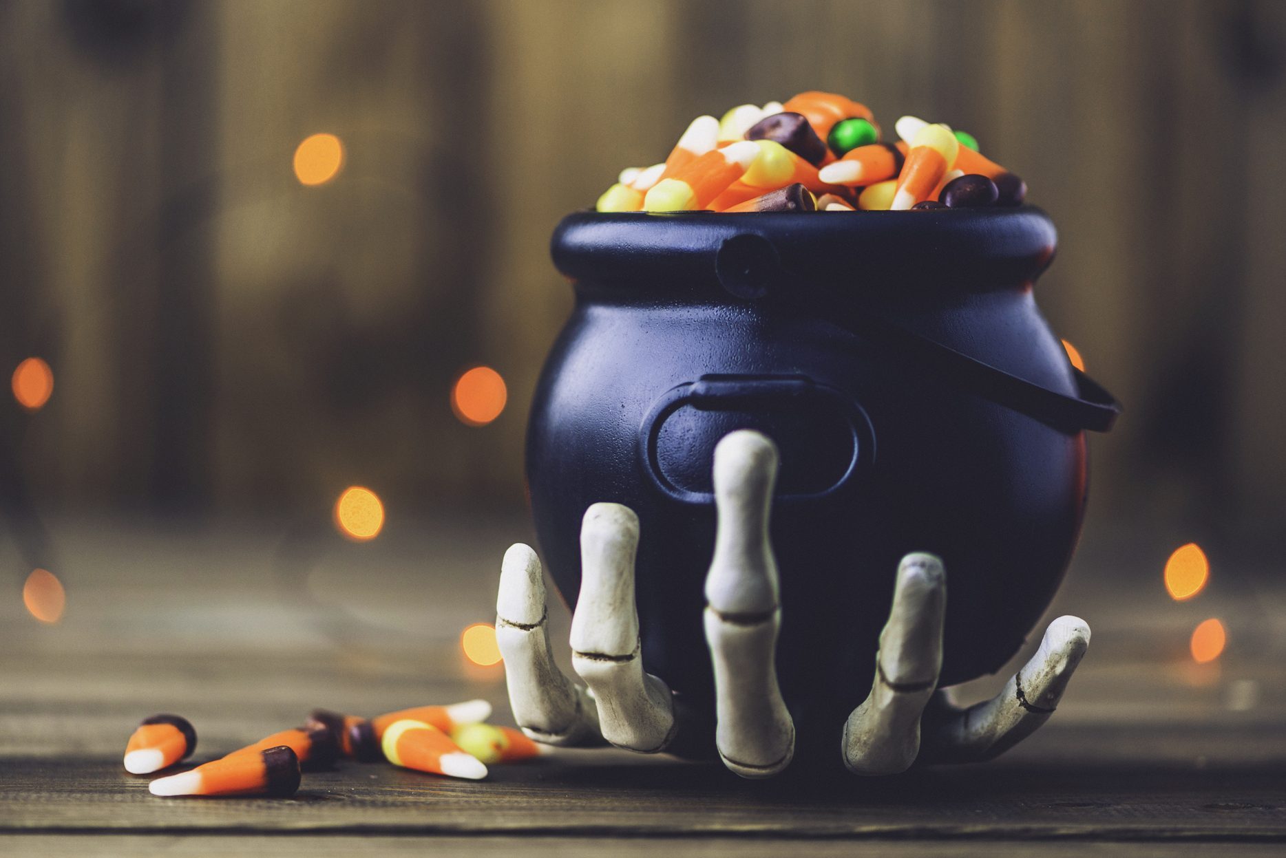 Skeleton hand holding cauldron with candy for halloween party decor
