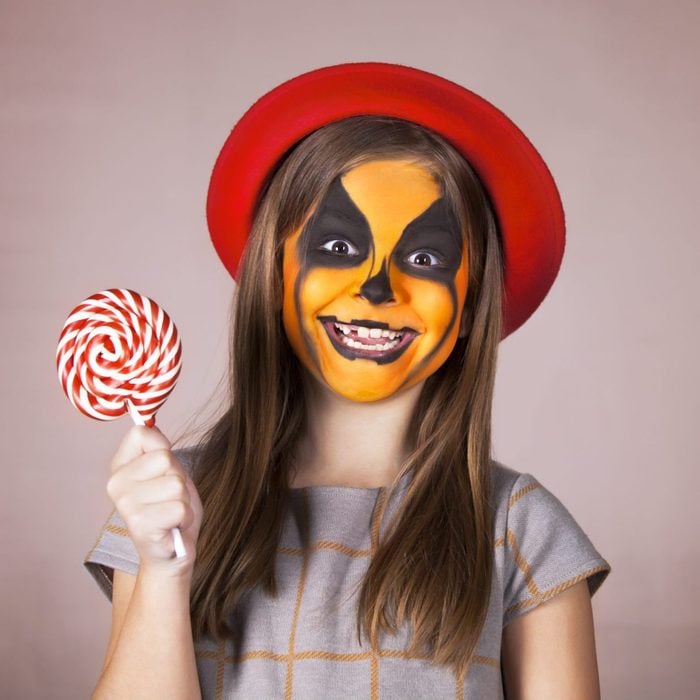 young girl with pumpkin face paint for halloween