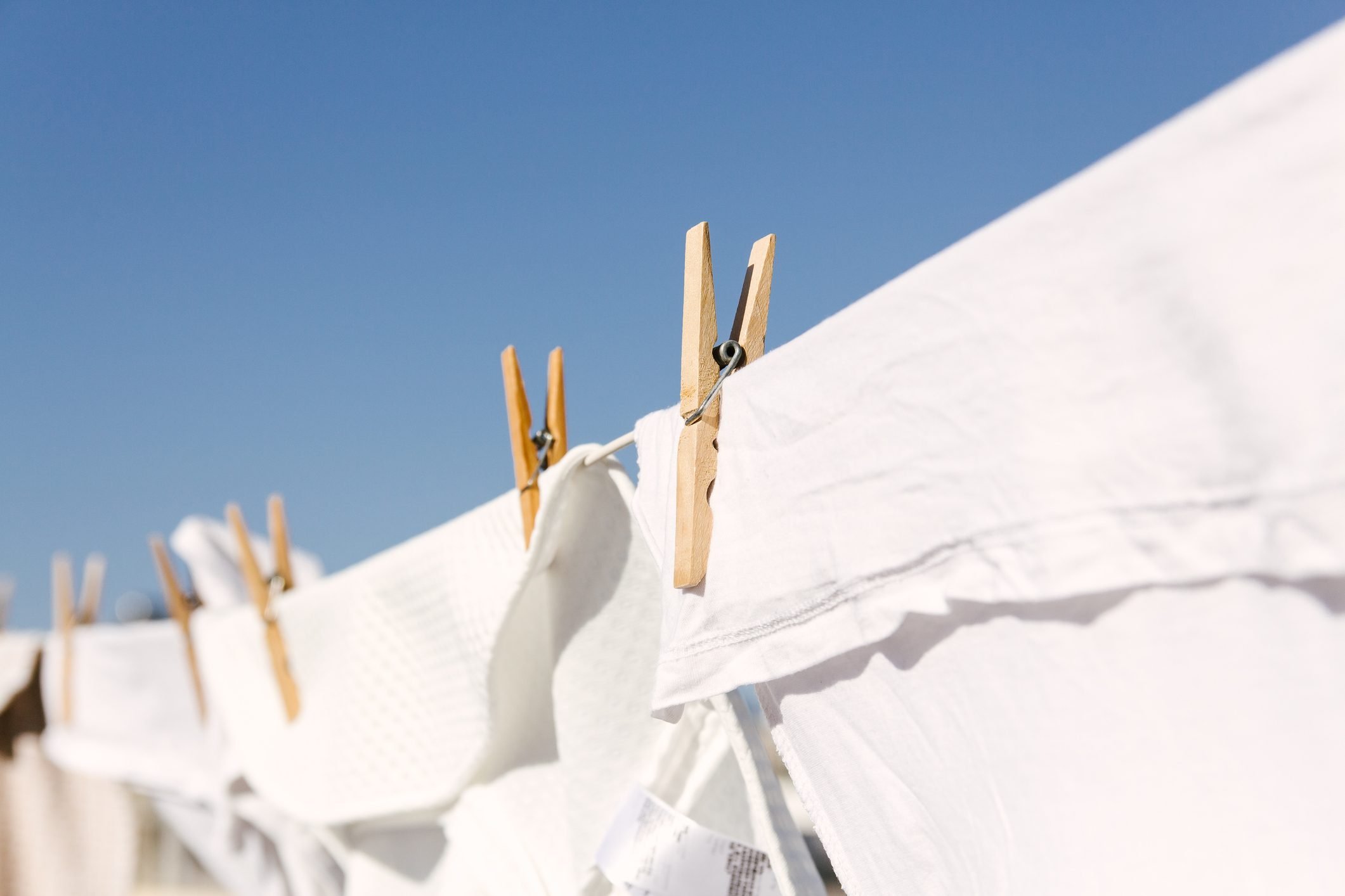 White shrunken clothes hung out to dry on a washing line in the sun.