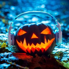 lit jack-o-lantern wearing headphones listening to halloween music