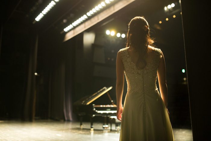 female Pianist walking towards a piano on stage