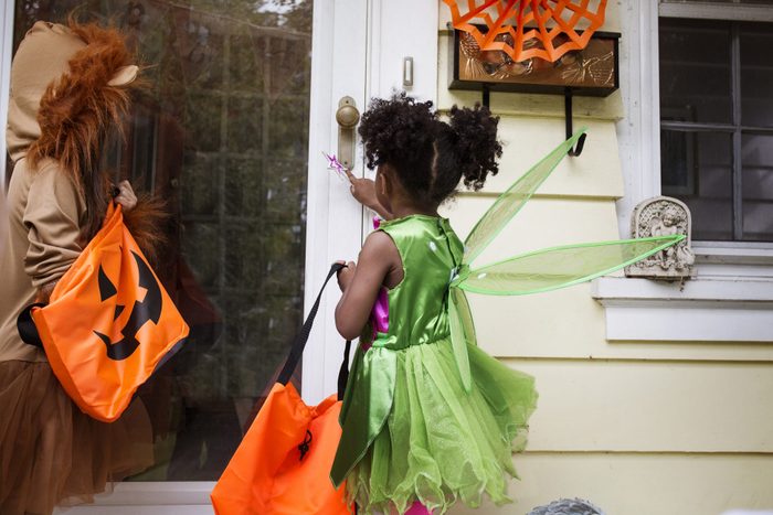 two children ringing doorbell while trick or treating on halloween