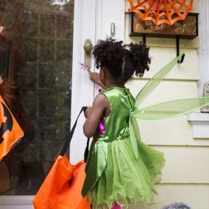 two children ringing doorbell while trick or treating on halloween