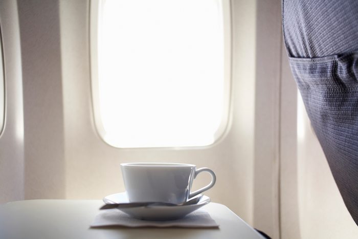Cup of coffee on airplane tray table by window
