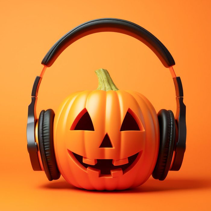 halloween jack-o-lantern wearing headphones on orange background