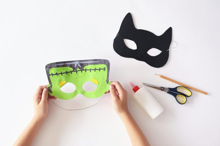 hands making paper halloween masks; cat and frankenstein masks