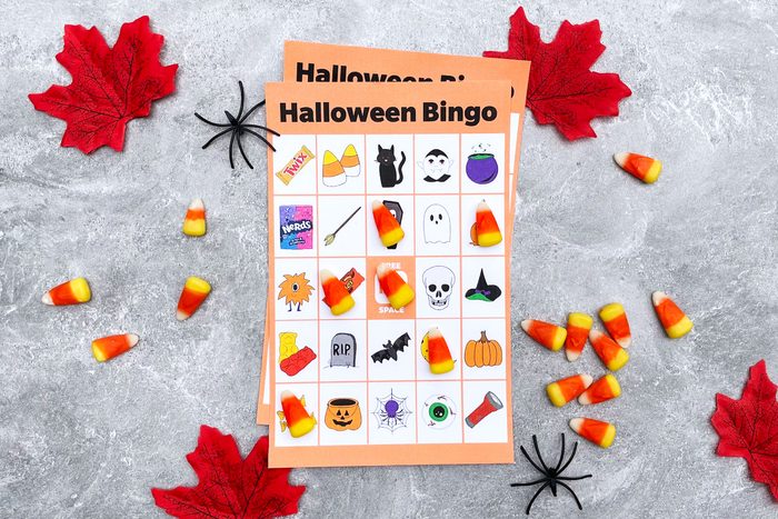 Halloween Bingo Card with candy corn, plastic spiders, and red autumn leaves on a gray textured background