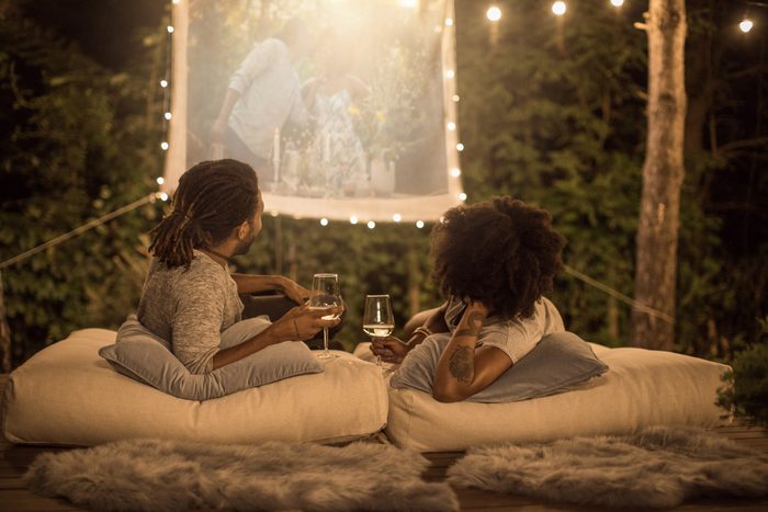 couple watching a movie outside in the backyard while drinking wine
