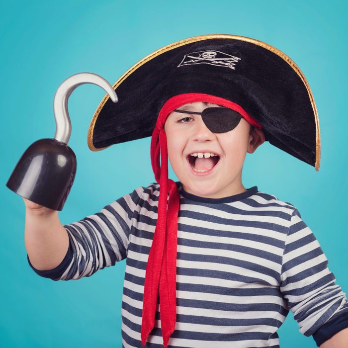 Portrait Of Happy Boy Wearing Pirate Costume While Standing Against Blue Background