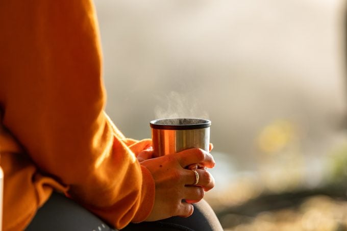 close up of person holding hot drink during the fall time outside