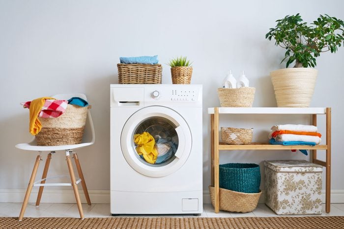 laundry room interior with clothes washer, laundry baskets, detergent and plant