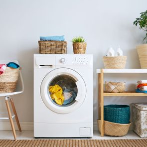 laundry room interior with clothes washer, laundry baskets, detergent and plant