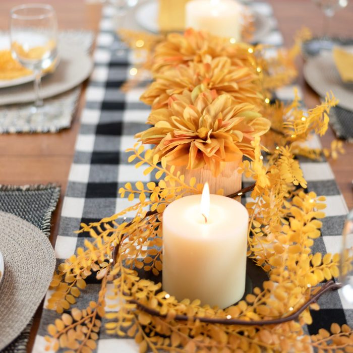 autumn dining table decorated with candles and gingham table runner