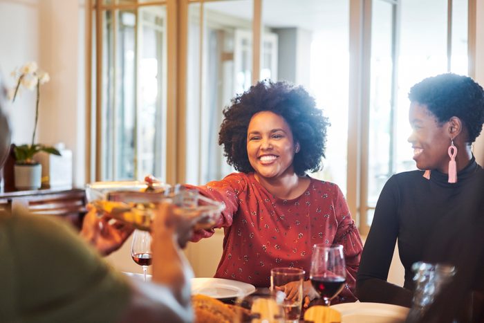 Smiling woman passing food to friend at thanksgiving party