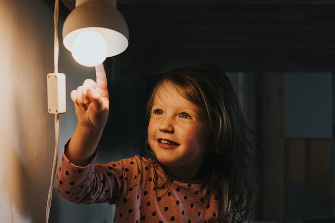Little girl pointing at a Light bulb in home