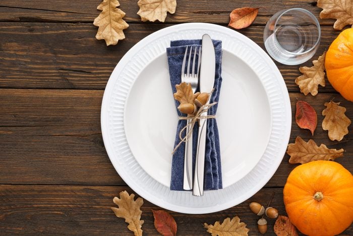 Thanksgiving Day table setting with leaves and pumpkins.