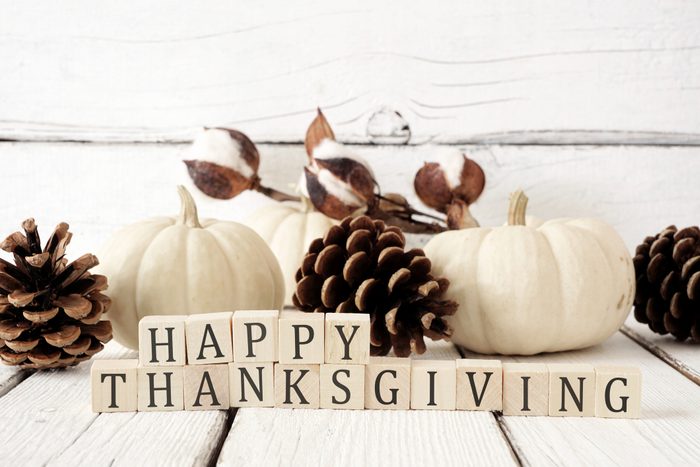 Happy Thanksgiving greeting against white wood with white pumpkins and brown autumn decor