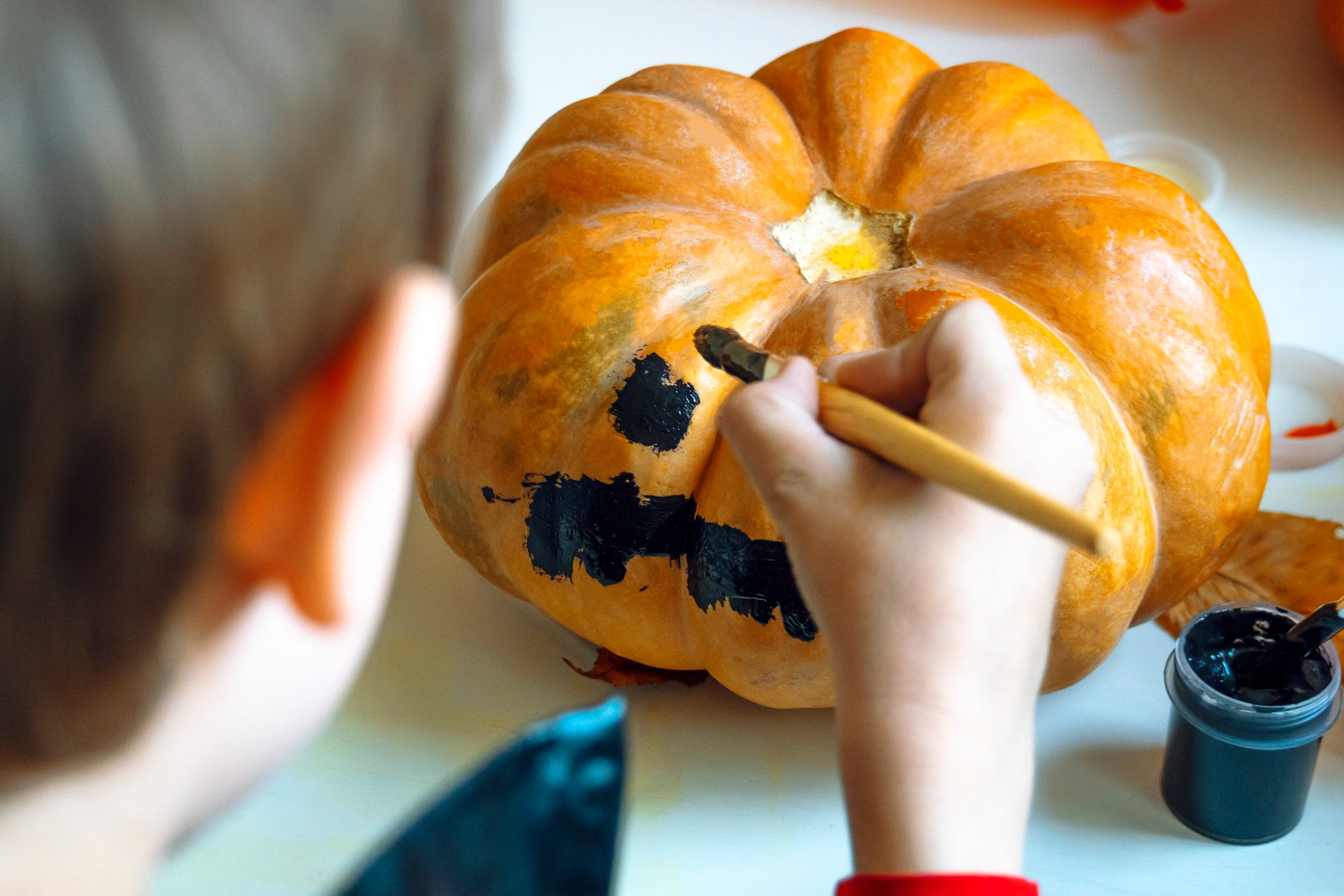 Rear View Of Boy Painting Pumpkin At Home