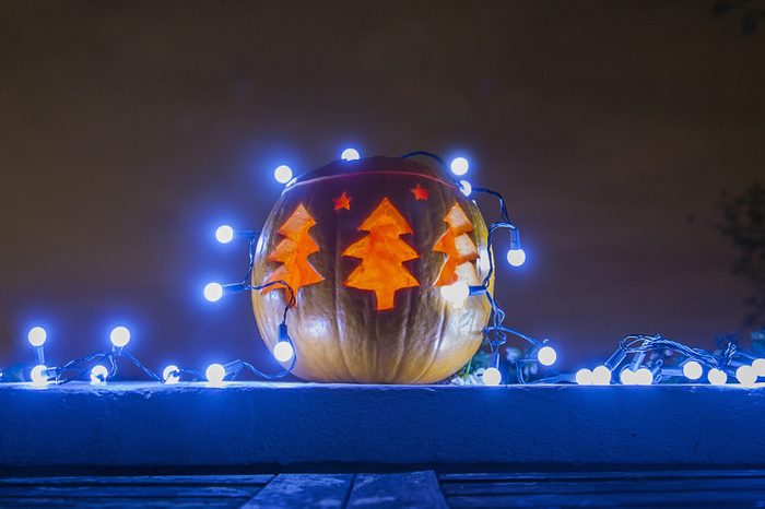 Jacko lantern decorated with blue Christmas lights glowing outdoors at night