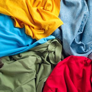 Lots of bright dirty colorful scattered clothes, abstract background. The concept of homework, lack of time for household chores.
