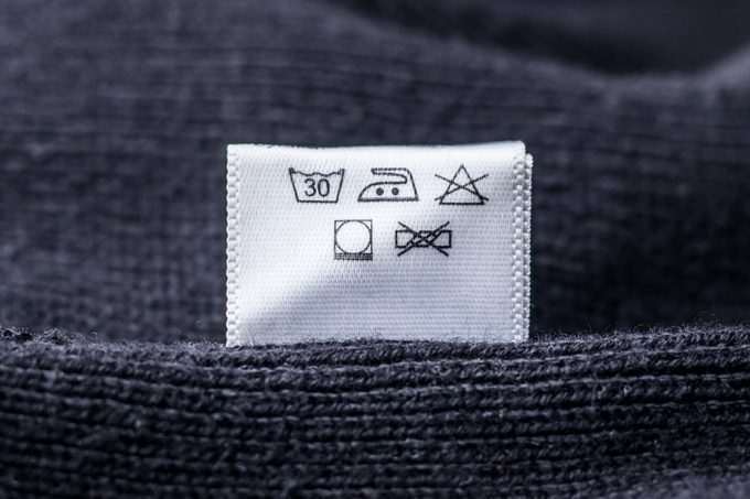 primer plano de los símbolos de lavandería en una etiqueta de cuidado de un suéter de lana gris oscuro