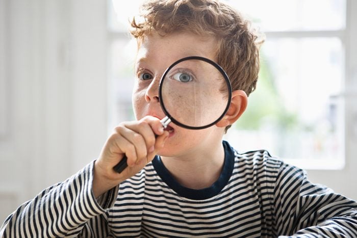 boy playing live clue with magnifying glass