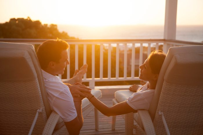 Couple on a romantic getaway vacation smiling with each other while watching the sunset at a resort