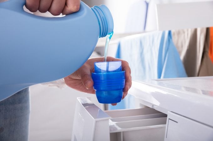 Person Pouring Detergent In Lid