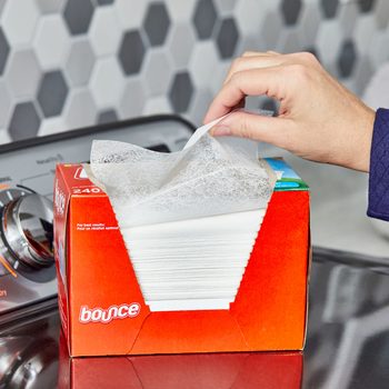 hand pulling a dryer sheet out of the box which is sitting on a washing machine in a laundry room