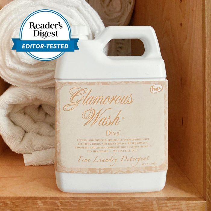 Tyler Glamorous Wash Diva Fine Laundry Detergent on a wooden shelf next to rolled up white towels