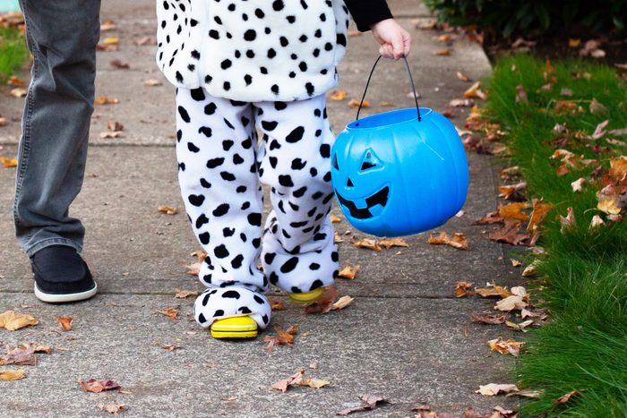 close up of anonymous child in a halloween costume holding a blue pumpkin candy bucket