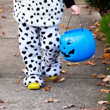 close up of anonymous child in a halloween costume holding a blue pumpkin candy bucket