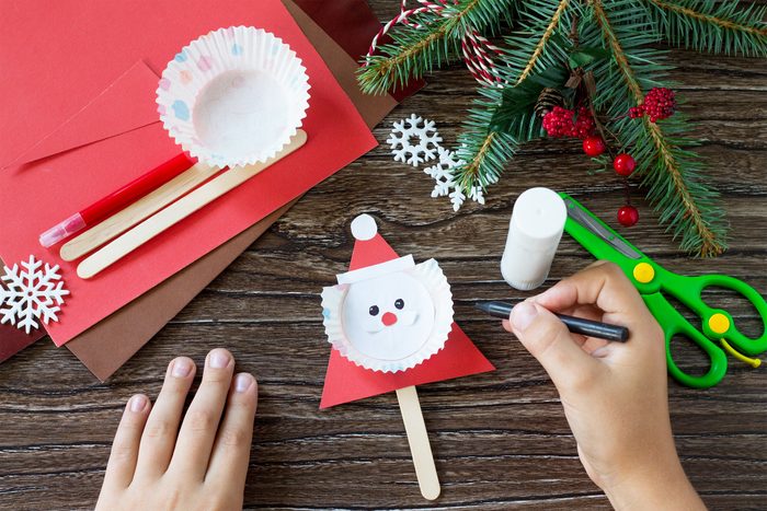The child draws details Christmas Santa stick puppets