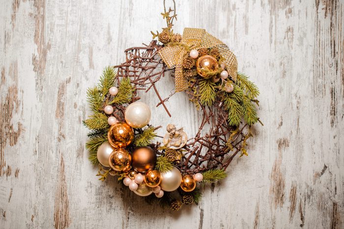 Christmas wreath made of fir tree and branches decorated with golden glass balls and bow