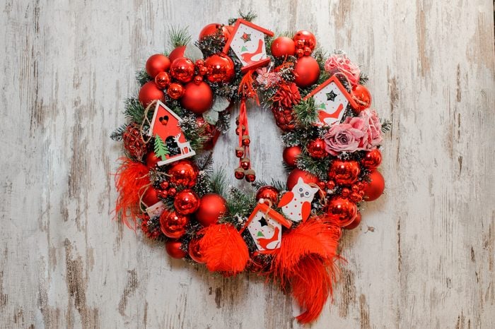 Christmas Wreath decorated with red balls, bows, roses and toy houses