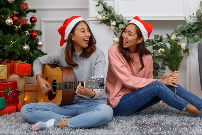 two sisters singing christian christmas carols around the christmas tree