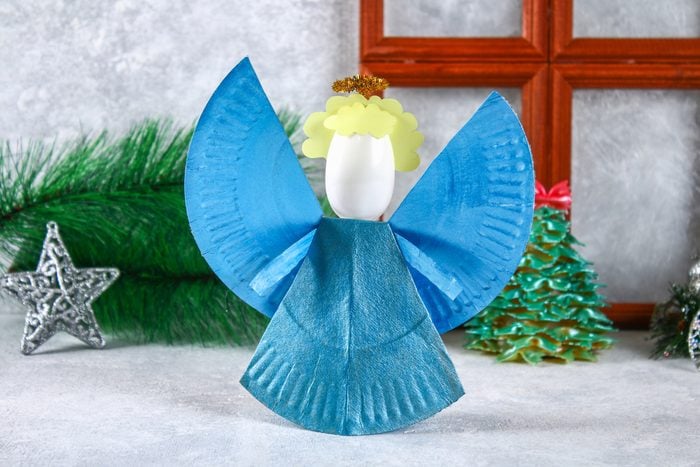 Christmas angel made from a disposable cardboard plate, a plastic spoon and paper