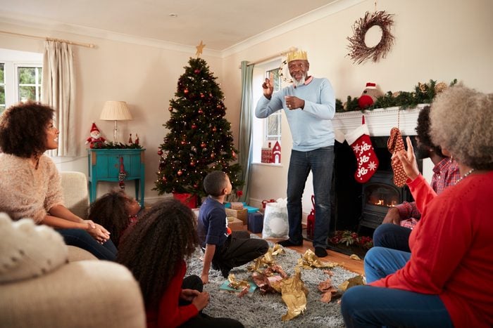 Multi Generation Family Playing Game Of Charades As They Celebrate Christmas At Home Together