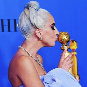 Lady Gaga posing with trophy at golden globes award show